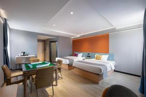 Jun Select Hotel Hubei Wuhan Hanjiang District Liuduqiao Metro Station في ووهان: غرفة في الفندق بسريرين ومكتب مع طاولة