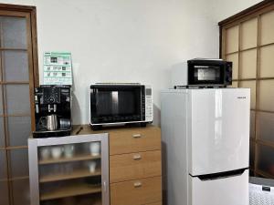 a kitchen with two microwaves on top of a refrigerator at Tora House in Nagoya