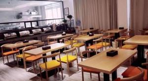 a restaurant with tables and yellow chairs in a room at GreenTree Inn Heze Railway Station Hotel in Zhaolou