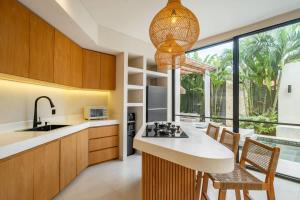 eine Küche mit Holzschränken und einem großen Fenster in der Unterkunft Vela Villa Pererenan Bali 2 Beds with Private Pool in Mengwi