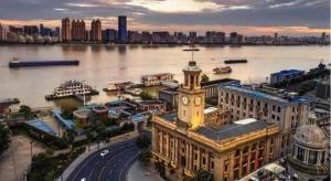 un bâtiment avec une tour d'horloge à côté d'une rivière dans l'établissement Lavande Hotel Wuhan Huanghelou Branch, à Wuhan