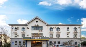 un grand bâtiment blanc avec une enseigne dessus dans l'établissement 7 Days Inn Qingdao Liaoyang West Road Xinye Plaza Metro Station, à Qingdao