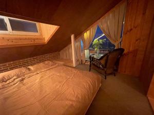 une chambre avec un lit, une chaise et une fenêtre dans l'établissement LaniKai Full oceanview stay, à Namae-ri