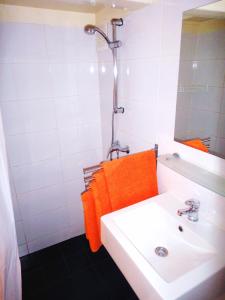 baño con lavabo blanco y toalla de color naranja en Orange Suite Studio, en Ámsterdam
