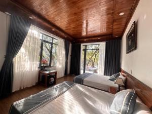 a bedroom with two beds and a wooden ceiling at Tràng An Riverbank Homestay in Nguyên Ngoại