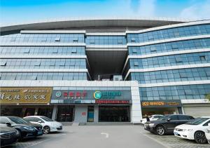 un grande edificio con auto parcheggiate in un parcheggio di City Comfort Inn Wuhan High Speed Railway Station a Wuhan