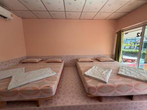 two beds sitting in a room with a window at ปลาตอง รีสอร์ท in Chao Lao Beach
