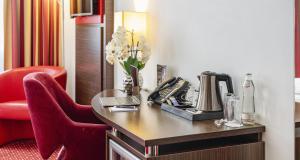 a hotel room with a desk with a phone and a chair at PLAZA INN Amedia Wien in Vienna +51 photos