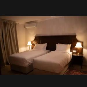 two beds in a hotel room with two lamps at John Bull House in Buzău
