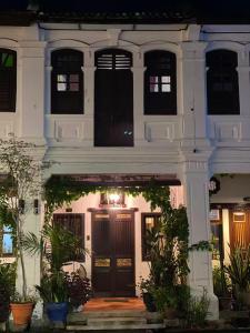 Qiyis Cottage في جورج تاون: بيت أبيض بأبواب ونباتات سوداء