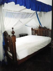a bedroom with a canopy bed with white sheets at Allison Homes in Kilifi