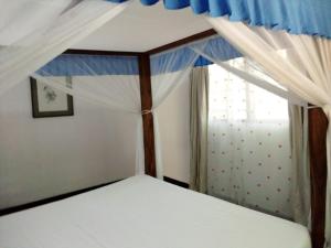 a bedroom with a canopy bed with a window at Allison Homes in Kilifi +23 photos