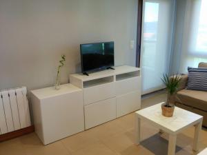 una sala de estar con TV en un centro de entretenimiento blanco en Apartamentos Lanceata I, en A Lanzada