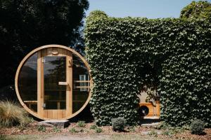 a round wooden door in a ivy covered building at Linnaeus Farm, Berry - by Linnaeus Collection in Berry