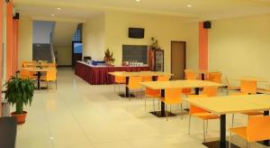 a restaurant with tables and chairs and a kitchen at Hotel Kings Kudus in Kudus