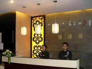 deux hommes debout à un comptoir dans un hall dans l'établissement Fairyland Hotel Kunming Tuodong Branch, à Kunming