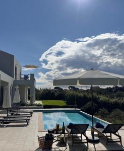 a swimming pool with two chairs and an umbrella at Villa Paradisio in EFL
