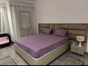 a bedroom with a bed with purple sheets and purple pillows at Grand appartement 3 chambres à la résidence valmascort Annaba in Annaba