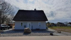 a small white house with a black roof at Ferienhaus In Mellnitz Mit Großem Garten in Poseritz