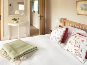 un lit blanc avec des oreillers et une serviette verte dessus dans l'établissement Fursdon Cottage, à Cadbury