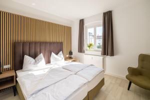 a bedroom with a large white bed and a chair at GSW Gästewohnungen Karl-Marx-Straße 42 in Sprucke