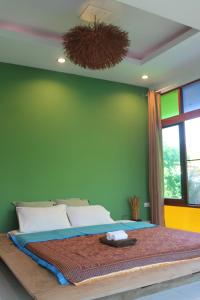 a bedroom with a large bed with a green wall at Open Mind Center Villas in Ban Tha Pai