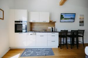 uma cozinha com armários brancos e uma mesa e cadeiras em Sonnenweg Appartements em Rust mais 23 fotografias