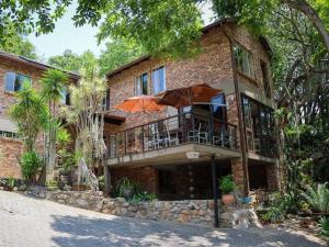 Casa de ladrillo con balcón y árboles en Willow Inn, en Nelspruit