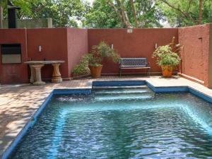 una piscina con un banco junto a una pared roja en Willow Inn, en Nelspruit