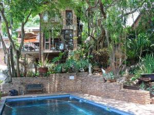 内尔斯普雷特Willow Inn的房子前面有一个砖砌游泳池，周围绿树成荫。