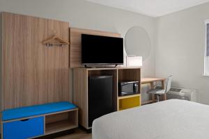 a bedroom with a bed and a television on a shelf at Days Inn by Wyndham Las Vegas in Las Vegas