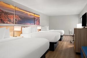 a hotel room with four beds and a tv at Days Inn by Wyndham Las Vegas in Las Vegas +22 photos