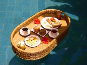 ein Tablett mit Frühstücksspeisen auf einem Tisch in einem Boot in der Unterkunft De Awan Villa in Kerobokan