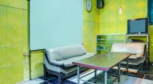 Zimmer mit 2 Stühlen, einem Tisch und einer Uhr in der Unterkunft OYO Life 91205 Rindang Guesthouse Syariah in Karawang