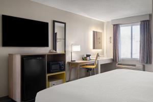 a hotel room with a bed and a flat screen tv at Days Inn by Wyndham Jamestown in Jamestown