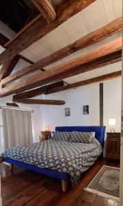 a bedroom with a blue bed in a room with wooden ceilings at Dolomites Luxury Penthouse in Agordo