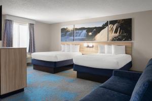 a hotel room with two beds and a couch at Days Inn by Wyndham Jamestown in Jamestown