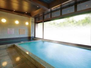 une piscine dans une salle de sport avec une grande fenêtre dans l'établissement Sakuraan Kawaguchiko Hotel, à Fujikawaguchiko