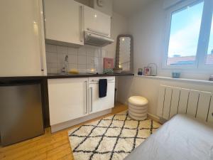 une cuisine avec des armoires blanches, un évier et une fenêtre dans l'établissement Le Coty, au Havre