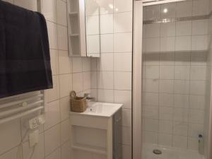 une salle de bain blanche avec lavabo et douche dans l'établissement Le Coty, au Havre