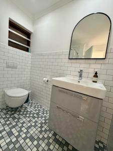 een badkamer met een wastafel, een toilet en een spiegel bij The Sultan Cottage in Stellenbosch