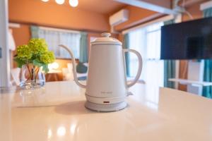 綺麗に改装されたアパートメント 京都や新大阪駅へアクセス良好 3ベッド 1バスルーム في أوساكا: غلاية كهربائية بيضاء موضوعة على طاولة بجانبها مزهرية