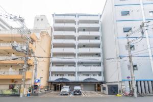 綺麗に改装されたアパートメント 京都や新大阪駅へアクセス良好 3ベッド 1バスルーム في أوساكا: مبنى سكني فيه سيارات تقف امامه