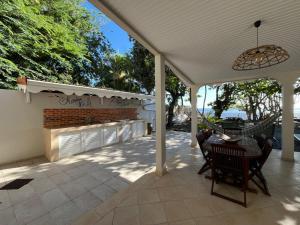 a patio with a table and chairs under a roof at Ti Kay Paradi T3 - Les pieds dans l'eau in Saint-Pierre
