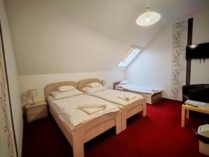 a bedroom with two beds and a red carpet at Menta Rooms & Bar in Kapuvár