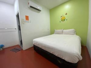 a bedroom with a white bed and a refrigerator at OYO 89671 Changlun Star Motel in Changlun
