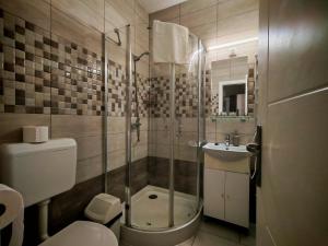 a bathroom with a shower and a toilet and a sink at Menta Rooms & Bar in Kapuvár