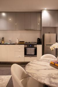 a kitchen with white cabinets and a table with chairs at Balcony, Free Parking, Workspace, Shared Pool & Gym in Melbourne