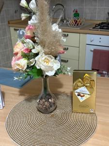 a vase of flowers on a table next to a box at Casa vacanza AIRPORT CALVO in Ronchi dei Legionari