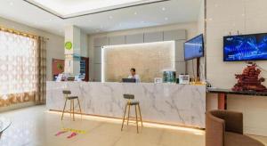 a woman is sitting at a counter in a lobby at GreenTree Inn Yancheng Dongtai West Wanghai Road Shell Hotel in Dongtai